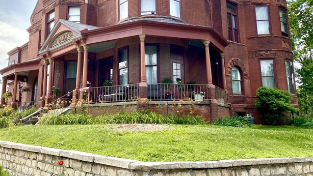 A large, historic brick building with a prominent tower, multiple windows, and a stone foundation. - Vineyard Mansion - Carriage House - 1 Queen 1 Full Bed (St Joseph)