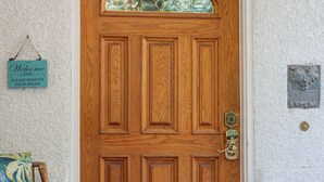 Eine Holztür mit Fensterglas, ein Willkommensschild und eine Fußmatte.