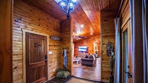A wooden cabin interior with a family room, a television, and a fireplace. - Luxurious cabin in the 💚 of town.  Construction near. (Broken Bow)