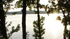 A wooden staircase leading to a deck overlooking a body of water, surrounded by trees. - Lake Barkley Log Cabin Getaway + Free Weekday Pontoon (seasonal)  (Cadiz)