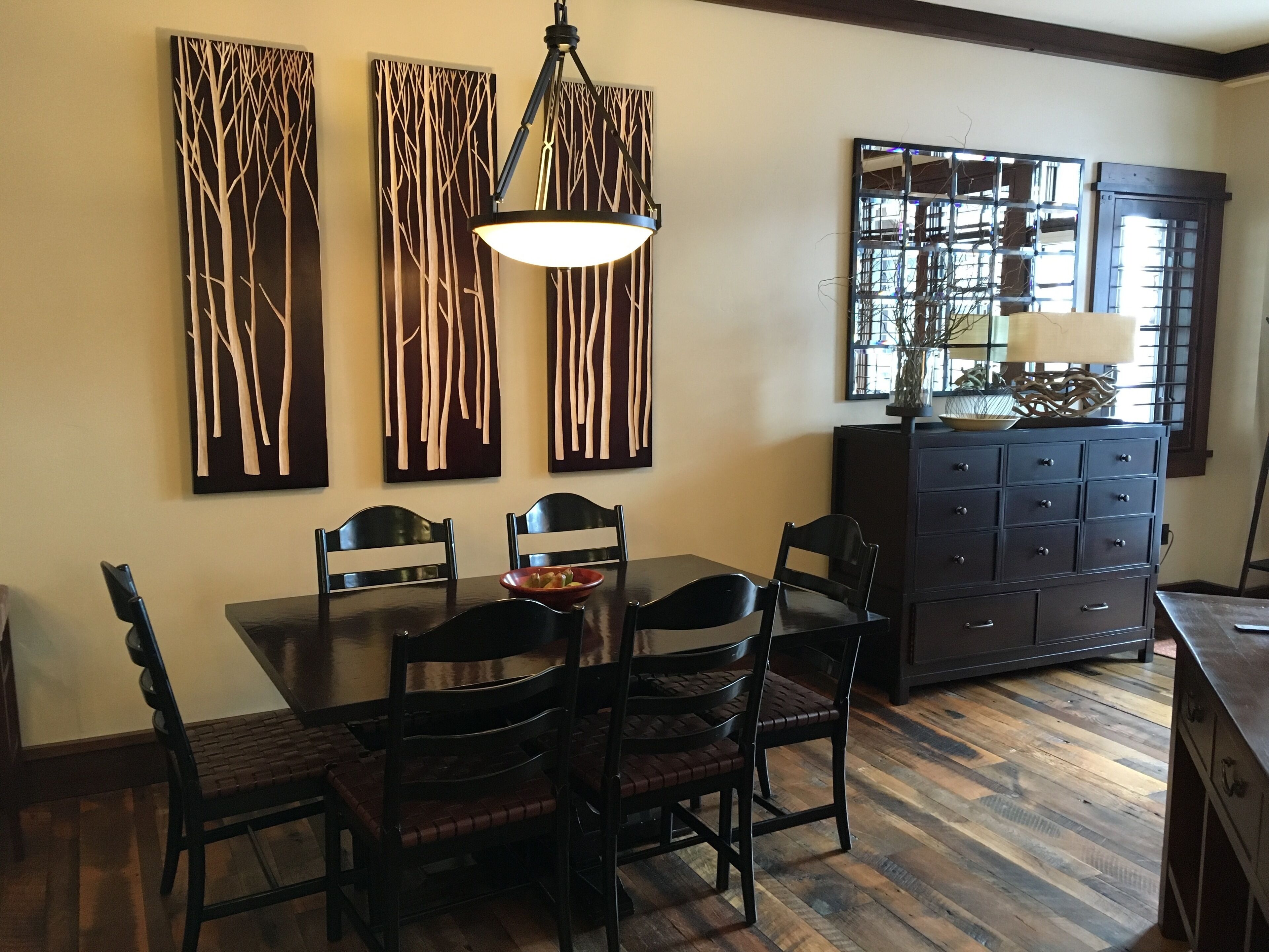 A dining area with a wooden table and chairs, a chandelier, and wall art.