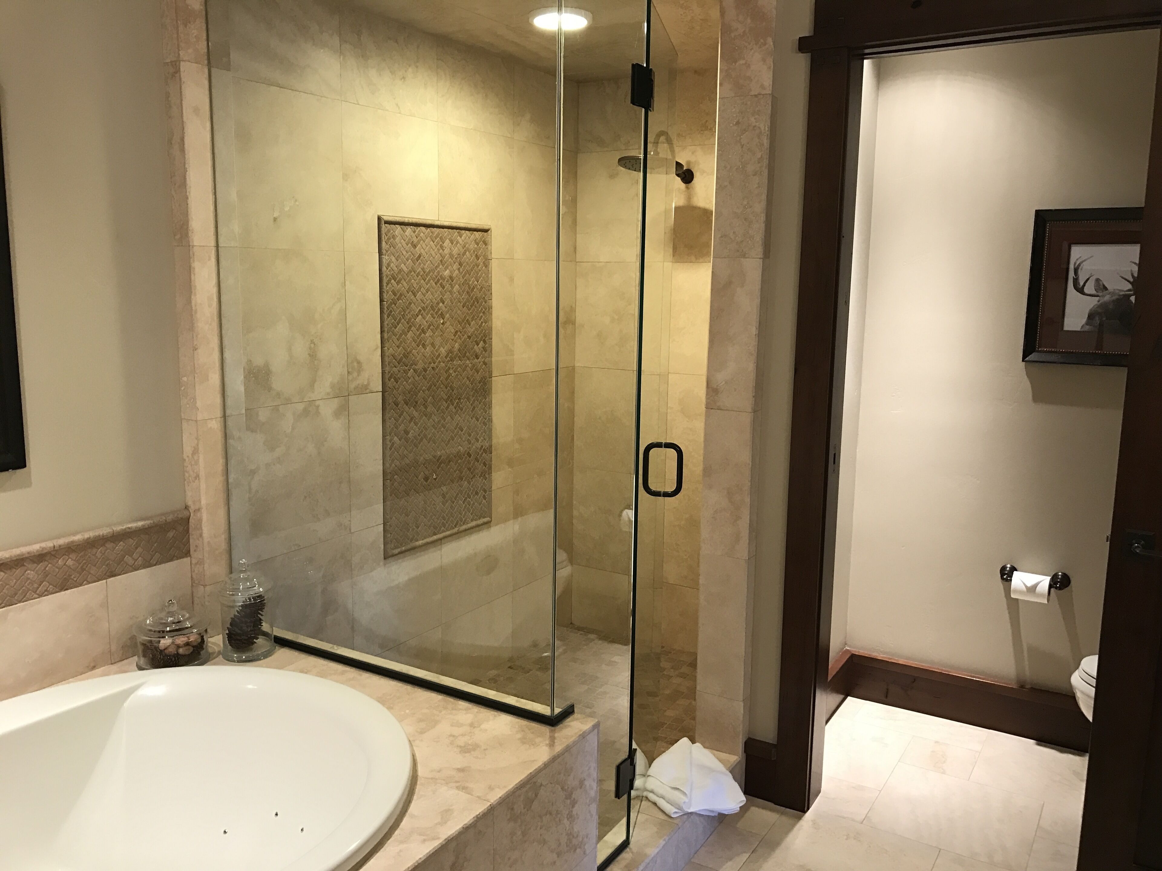 A modern bathroom with a glass-enclosed shower, a white bathtub, and a toilet.