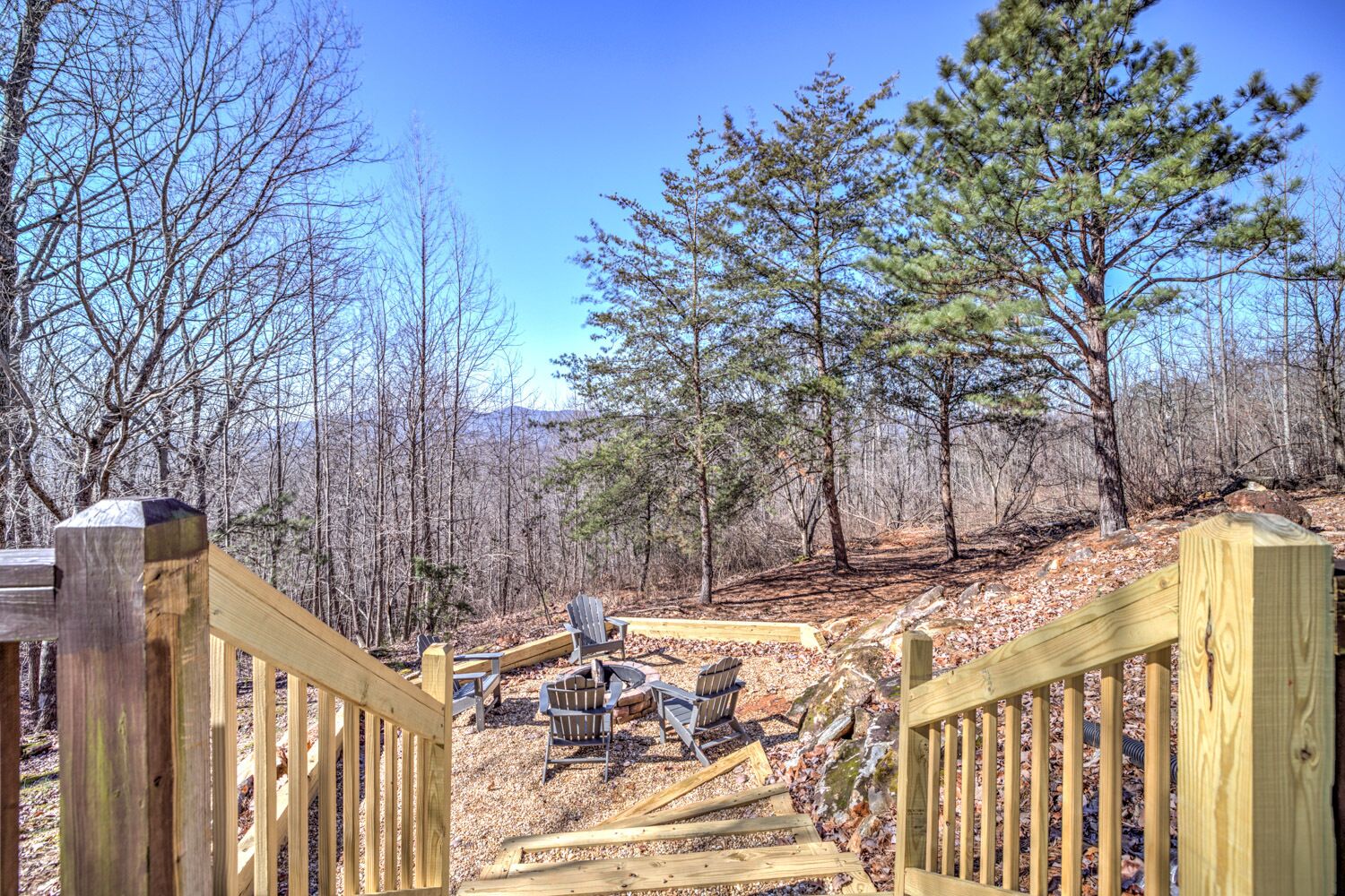 A wooden deck with a view of a forested area and a clear sky.