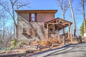 Situated on a paved driveway, this cabin features a simple design with a flat roof and a cozy porch.