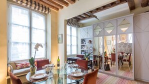 Un comedor con una mesa de vidrio, sillas rojas y vista a una cocina separada por un panel de vidrio.