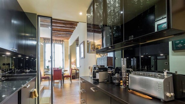 Una cocina moderna con armarios oscuros, una isla grande y un horno empotrado.