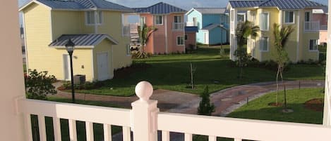 A row of colorful townhouses with a well-maintained lawn and a white fence in the foreground.
