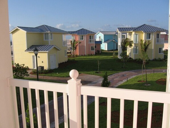 A row of colorful townhouses with a well-maintained lawn and a white fence in the foreground.