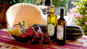 Un tavolo con due bottiglie di vino, un cesto di vimini e un piatto di verdure.