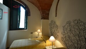 Una camera da letto con un letto, due lampade ai comodini, una finestra con vista e un elemento decorativo a parete in metallo.