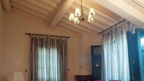 Zona pranzo con tavolo e sedie, un lampadario e tende.
