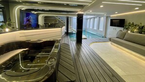 A modern interior with a wooden floor, a reception area, a pool, and a sofa.