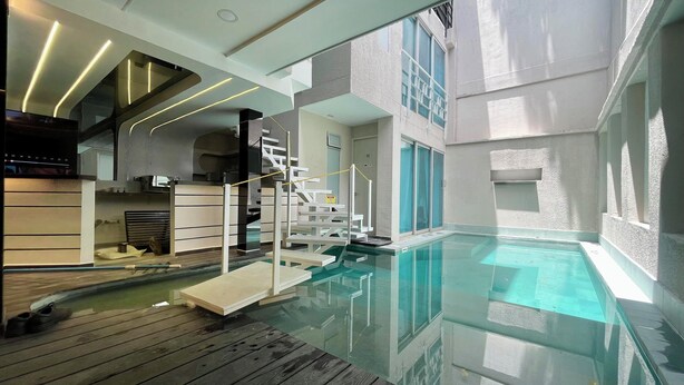 A modern indoor pool with clear glass walls, wooden deck, and contemporary interior design.
