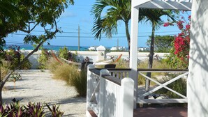 A coastal property with a white porch, a hammock, and a view of the ocean. - Exceptional ocean views, centrally located, just 1,700 ft off Grace Bay Beach (Providenciales)