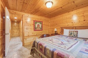 A wooden cabin room with a bed, a nightstand, a lamp, and a quilt. - Knotty Pine - A Fairy Tale Cottage Getaway (Sautee Nacoochee)