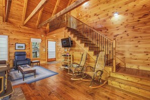 A wooden interior with a staircase, a television, and seating. - Knotty Pine - A Fairy Tale Cottage Getaway (Sautee Nacoochee)