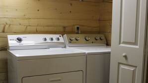 Un'area lavanderia con lavatrice e asciugatrice a carica frontale, pareti in legno e una porta bianca.