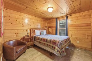 Ein Schlafzimmer einer Holzhütte mit Bett, Nachttisch, Stuhl und Fenster.