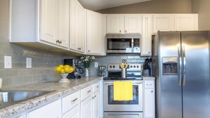 A modern kitchen with white cabinets, stainless steel appliances, and a granite countertop.