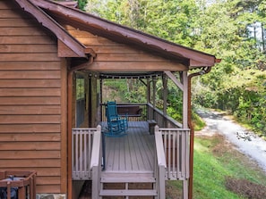 A wooden cabin with a porch, a bench, and a chair.