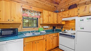 A wooden cabin kitchen with a microwave, sink, stove, and refrigerator. - Country Charm A - Pet Friendly Group Cabin (Helen)