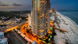A high-rise hotel with multiple floors, a pool area, and a beach view.