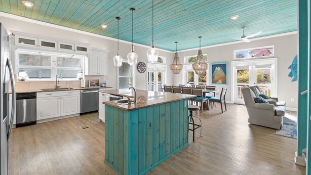 A modern kitchen with a central island, white cabinetry, and a teal ceiling.
