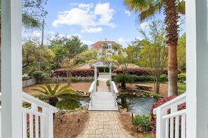 A pathway leading to a house with a red roof, surrounded by lush greenery and a small pond. - 🏆 BEST VALUES 30A Private beach & Private Heated Pool, fenced yd, bikes, pets (Santa Rosa Beach)