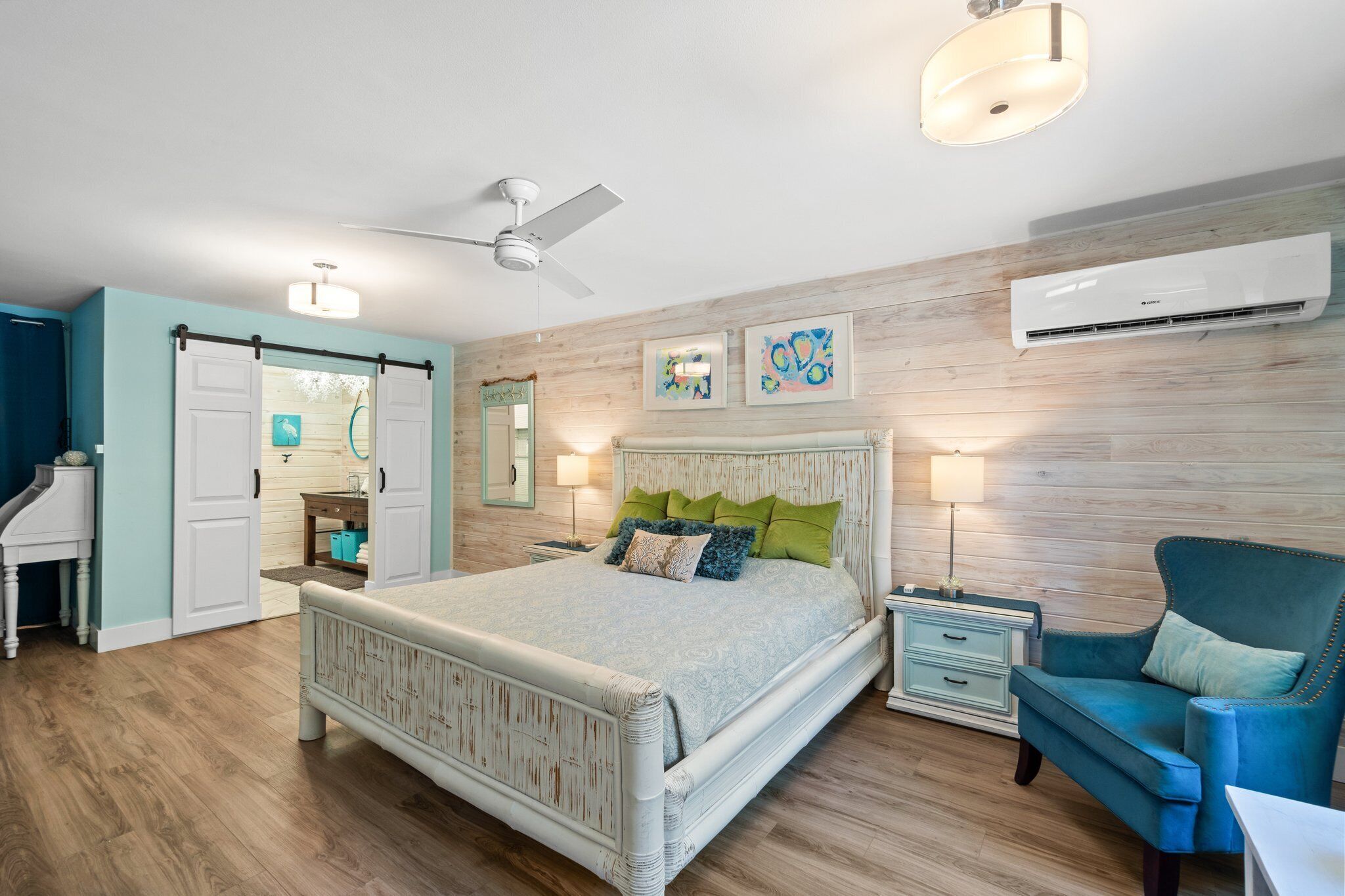 A bedroom with a bed, a chair, a desk, and an air conditioning unit.