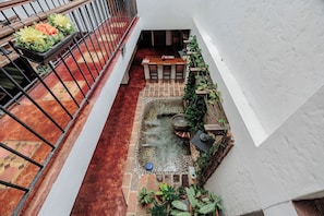 Un jardin sur le toit agrémenté d’un petit élément décoratif aquatique, de plantes en pot et d’un espace aménagé pour s’asseoir.