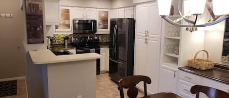A modern kitchen with white cabinets, stainless steel appliances, and a central island.