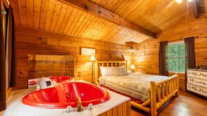 A wooden cabin room with a bed, a red bathtub, and a dresser with bird decorations. - Love Bird - The Perfect Nest! (Sautee Nacoochee)