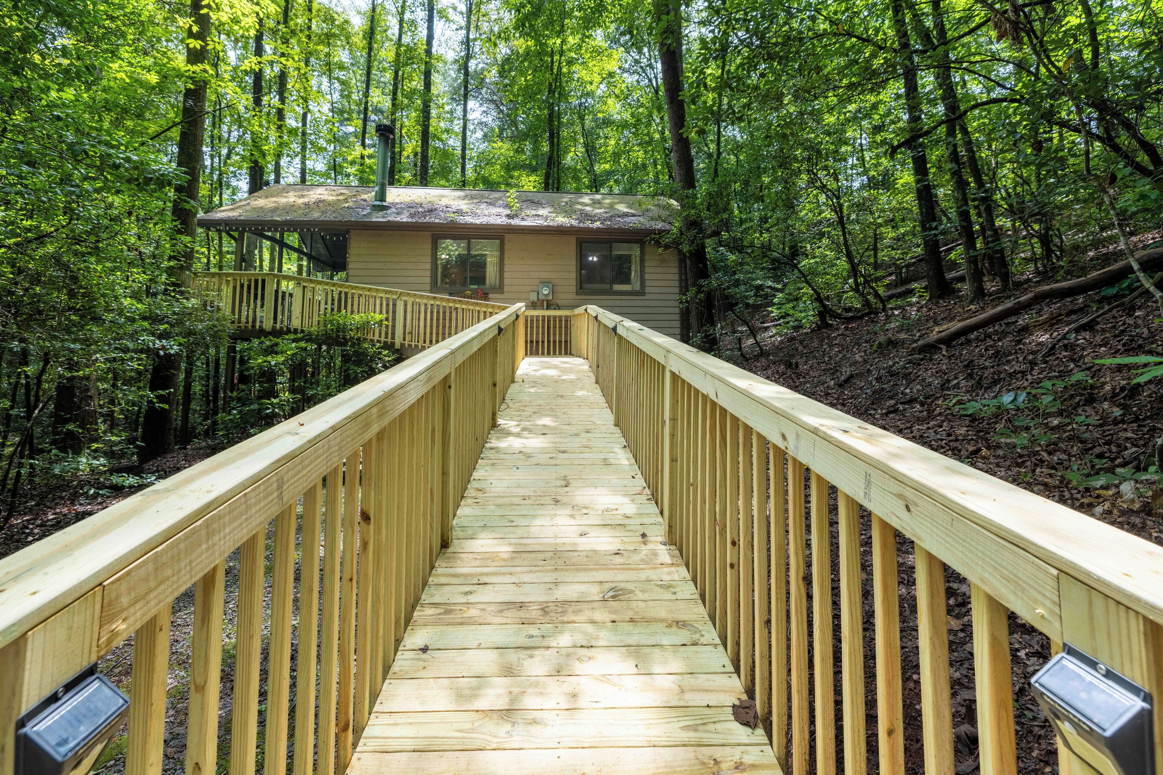 Une terrasse en bois menant à un chalet situé dans une forêt.