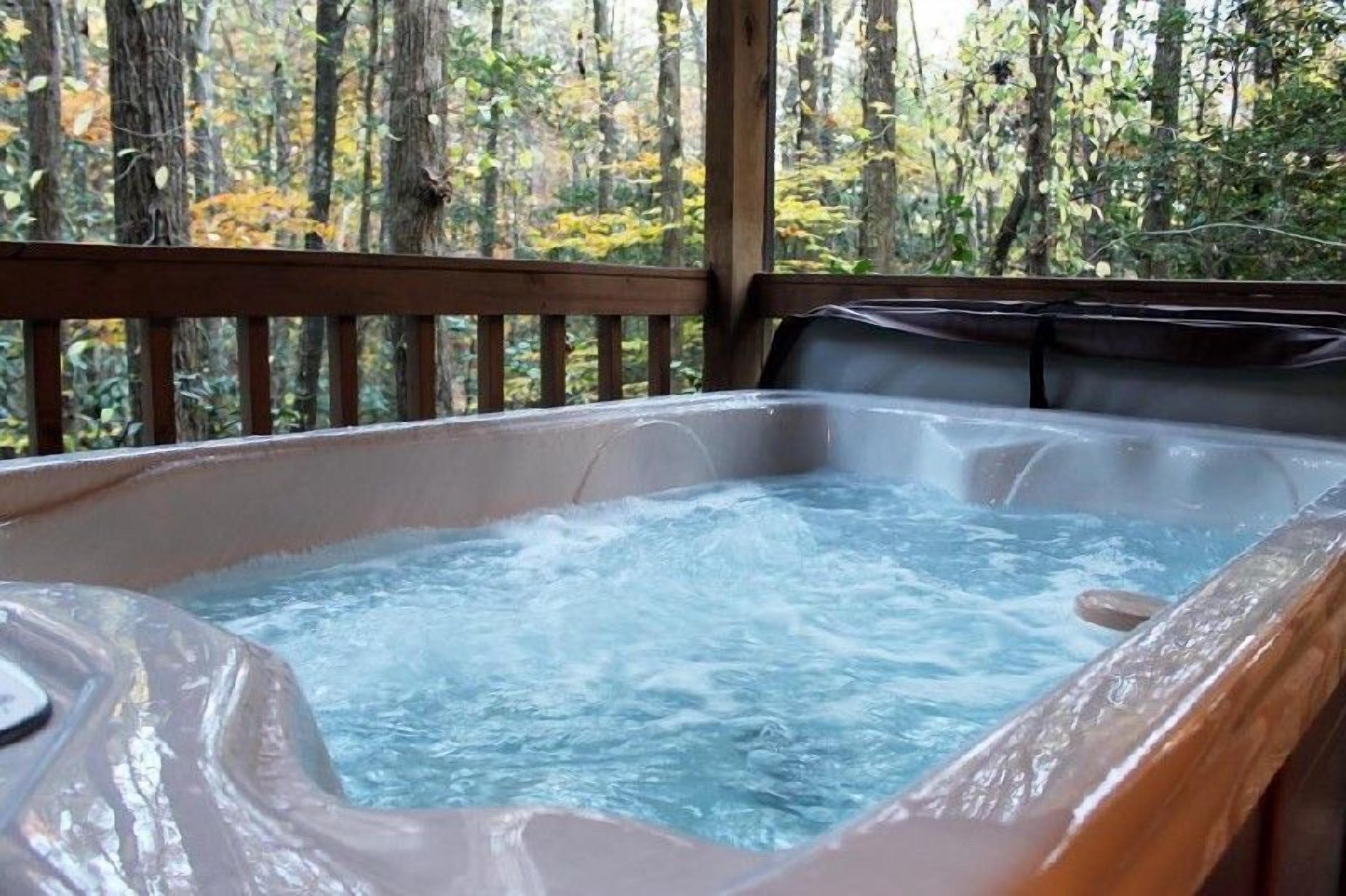 Un jacuzzi con terraza de madera y vista al bosque.