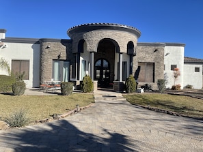 A modern house with a circular stone entrance, large windows, and a well-maintained lawn.
