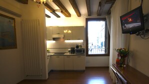 A compact kitchen with white cabinets, a microwave, and a coffee maker. There's a window with a view of buildings outside. - Grand Canal Apartment...Venetian Dream!!! All Inclusive Options! No Extras -WiFi (Venice)