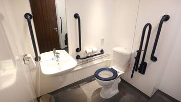 A bathroom with a white sink, a toilet with a blue seat, and black grab bars.