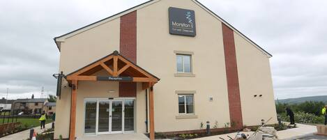 A building with a reception area, a sign reading "Marston's," and a paved entrance.