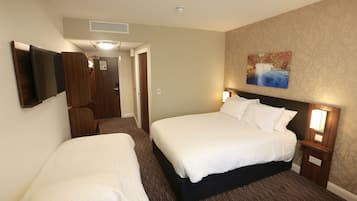 Ein Hotelzimmer mit zwei Betten, einem Fernseher und einem Bild an der Wand.