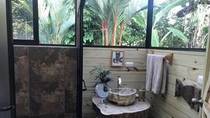 Une salle de bain avec un lavabo en pierre, des murs en bois, un tableau encadré et un porte-serviettes.