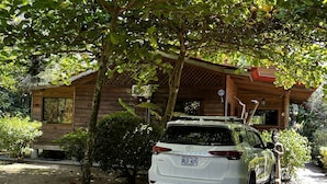 Un VUS Toyota blanc est garé devant une cabane en bois dotée d’un porche abrité.