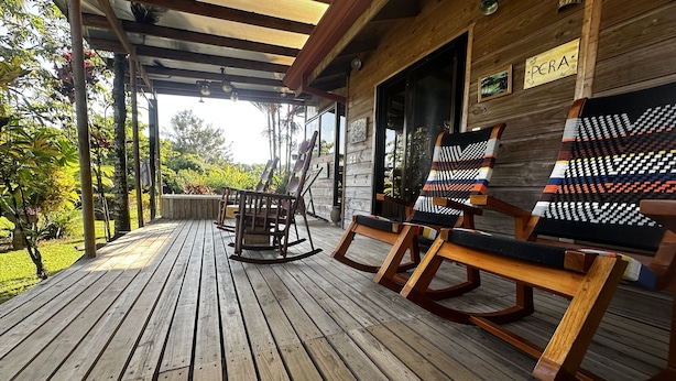 Une terrasse en bois avec des fauteuils à bascule et une pergola.