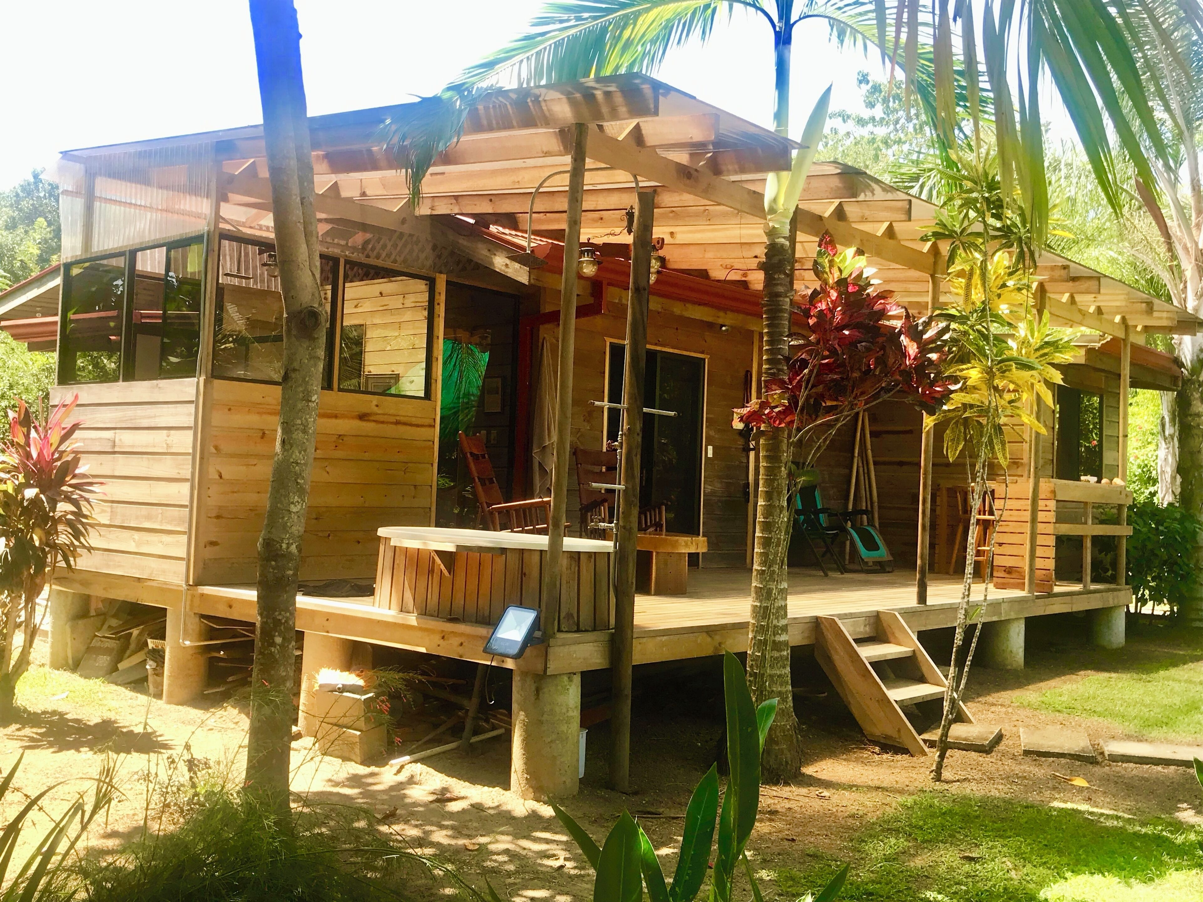 A wooden house with a porch, a small deck, and a staircase leading to the upper level.