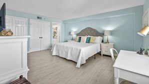 A bedroom with a bed, bedside tables, a desk, and a chair.