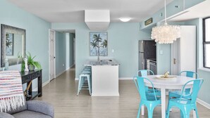 A modern kitchen with a white island, blue chairs, and a hanging light fixture.