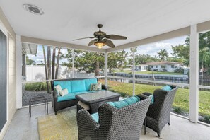 A covered patio with wicker furniture, a ceiling fan, and a view of a residential area. - Beautiful 3BD,2BA Waterfront Pool Home (Saint Petersburg)