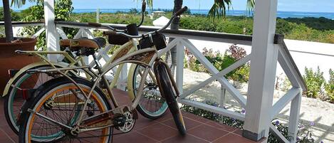 A bicycle parked on a tiled patio with a view of the ocean and palm trees.