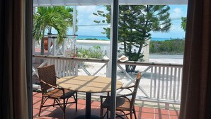 Un balcone con mobili in vimini, vista sull'oceano e un pergolato bianco.