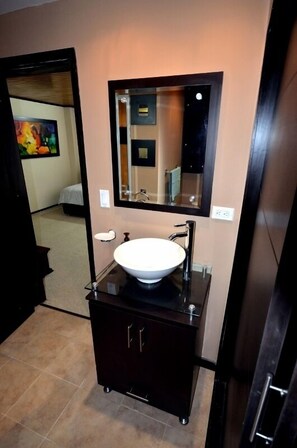 Une salle de bain moderne avec un lavabo blanc, des meubles de rangement aux couleurs foncées et un grand miroir.