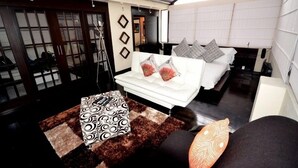 Un intérieur moderne avec un canapé blanc, un lit agrémenté d’oreillers à motifs et une petite table sur laquelle est posée une nappe décorative.